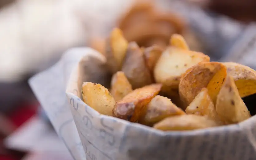 Patate al forno: come prepararle croccanti e saporite. Cestino con patatine e tovagliolo rosso.
