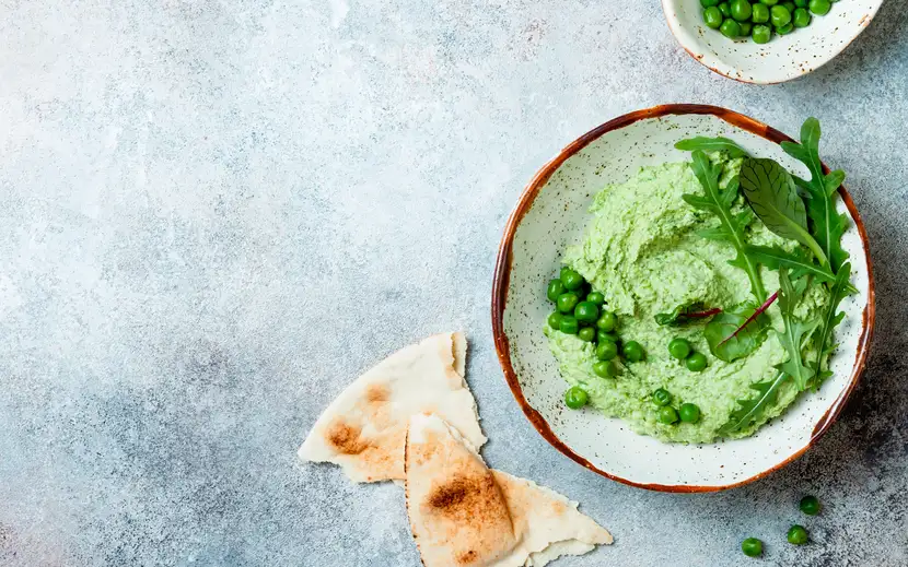 Hummus di piselli Orogel per ricette leggere: ciotola di hummus verde con croccanti patatine pita.