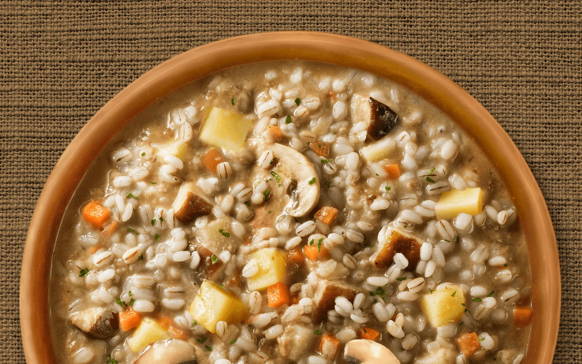 Zuppa Orzo e Funghi Orogel, un classico confortante e nutriente, servita in ciotola su tavolo.