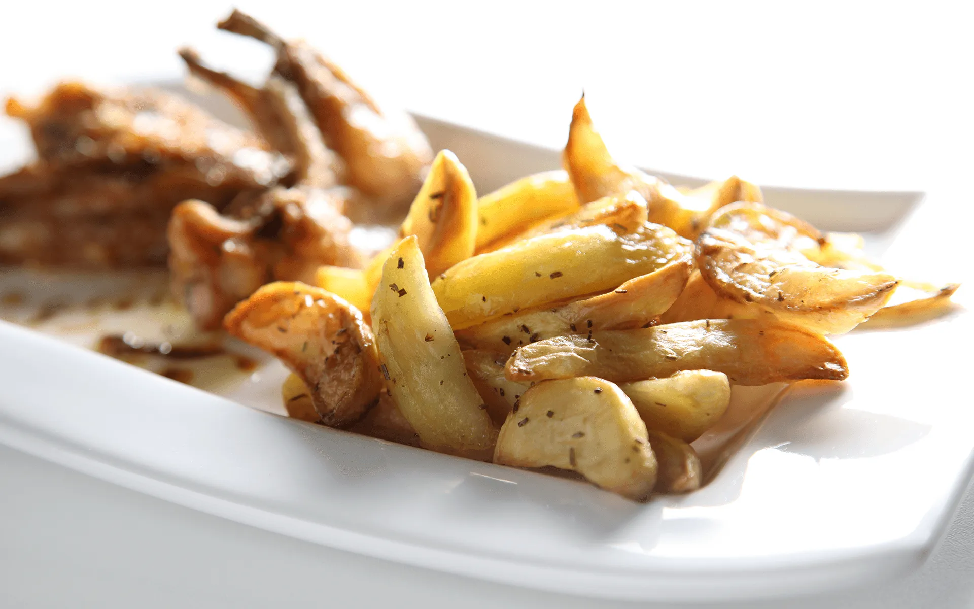  L'immagine mostra delle patate a spicchi al forno con del rosmarino perfettamente dorate e gustose.